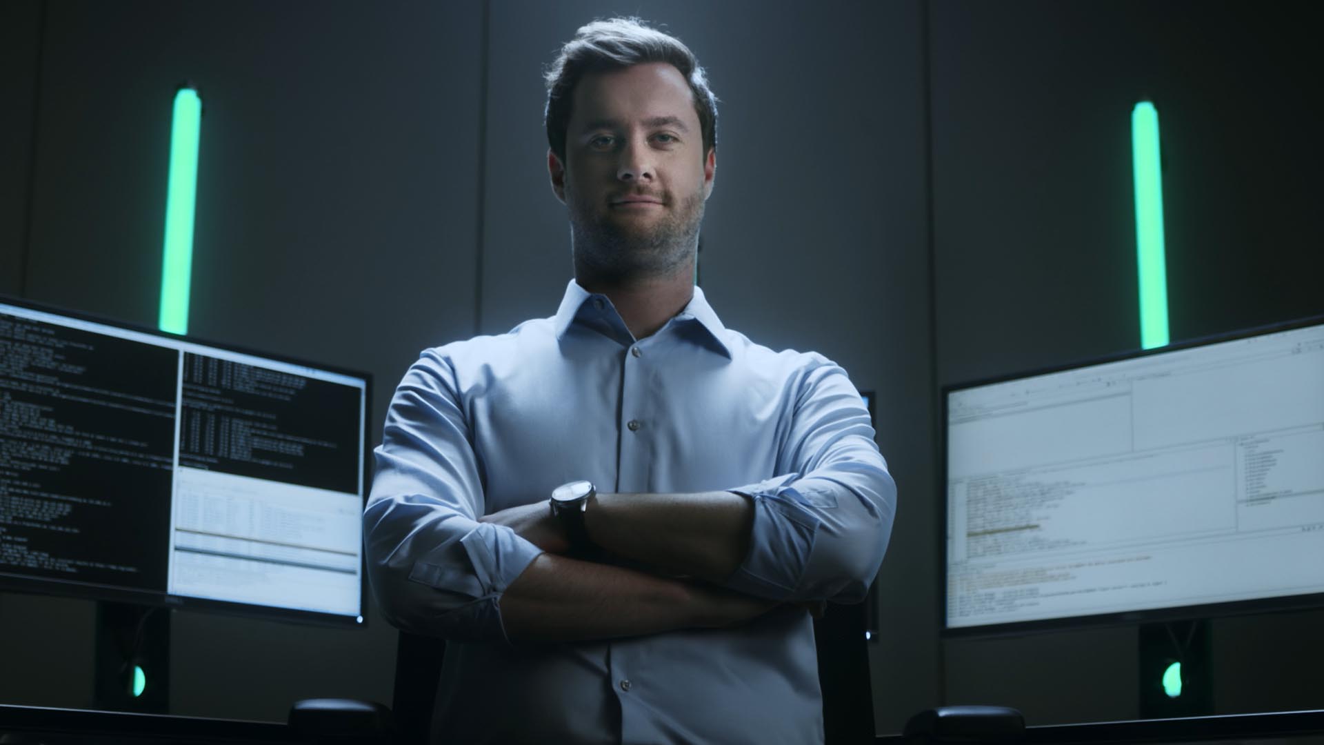 Ausschnitt aus dem Fraunhofer Recruitingspot, Mann steht zufrieden vor einigen Bildschirmen welche komplexen Code anzeigen