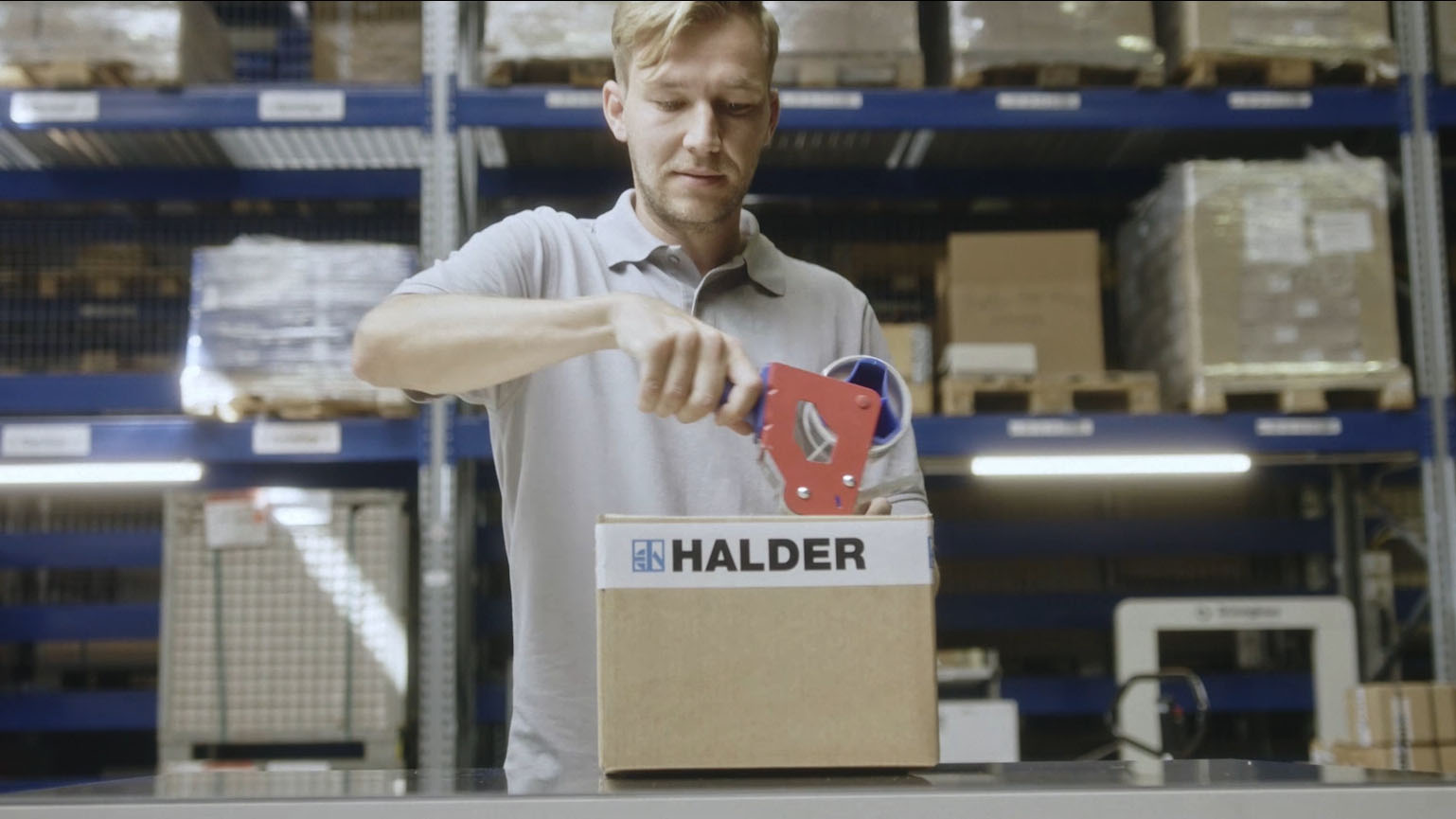 Aus dem Halder Inside Imagefilm - Mann verpackt Paket von Halder